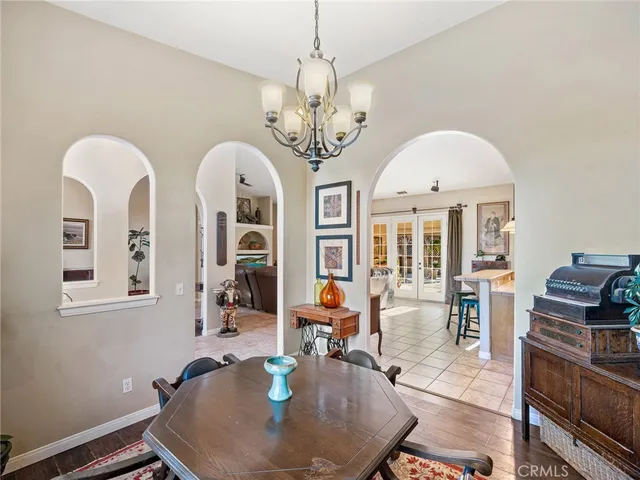 a dining room with wooden floor a chandelier a wooden table and chairs