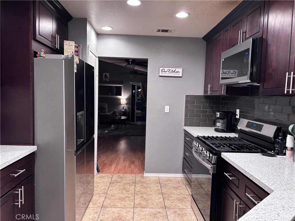 560 Coudures Way Perris, CA 92571 - Photo 32 of 35 a kitchen with stainless steel appliances granite countertop a refrigerator and a stove top oven