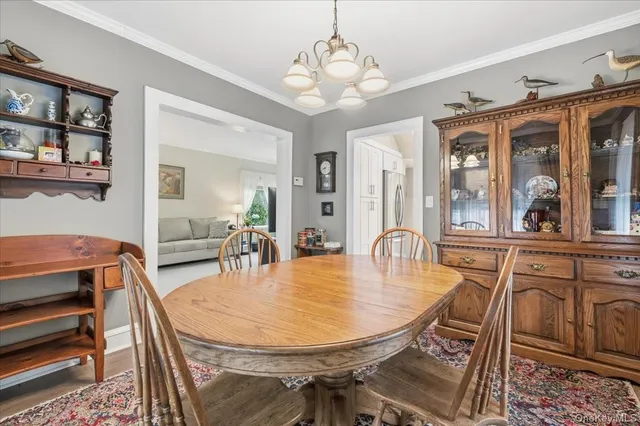 a dining room with wooden floor a chandelier a wooden table and chairs