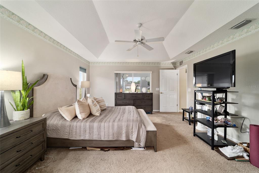 5245 Northwest 21st Loop Ocala, FL 34482 - Photo 14 of 26 a bedroom with a bed a mirror on dresser and a flat screen tv