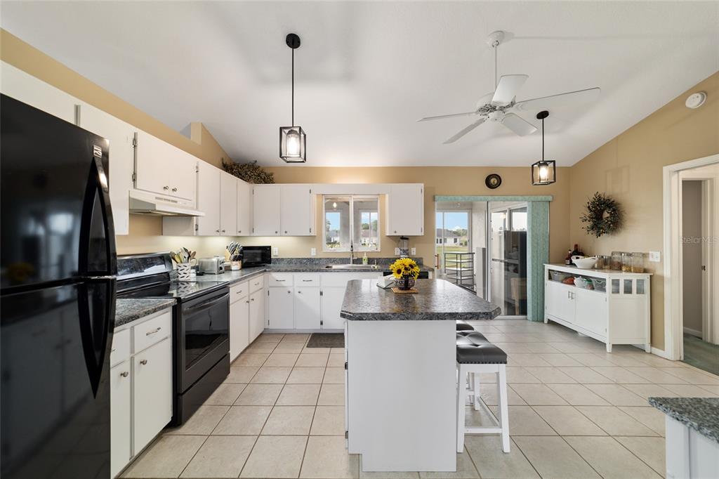 5245 Northwest 21st Loop Ocala, FL 34482 - Photo 9 of 26 a kitchen with stainless steel appliances kitchen island granite countertop a refrigerator a stove a sink and white cabinets with a dining table