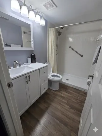a bathroom with a sink a toilet a mirror and shower