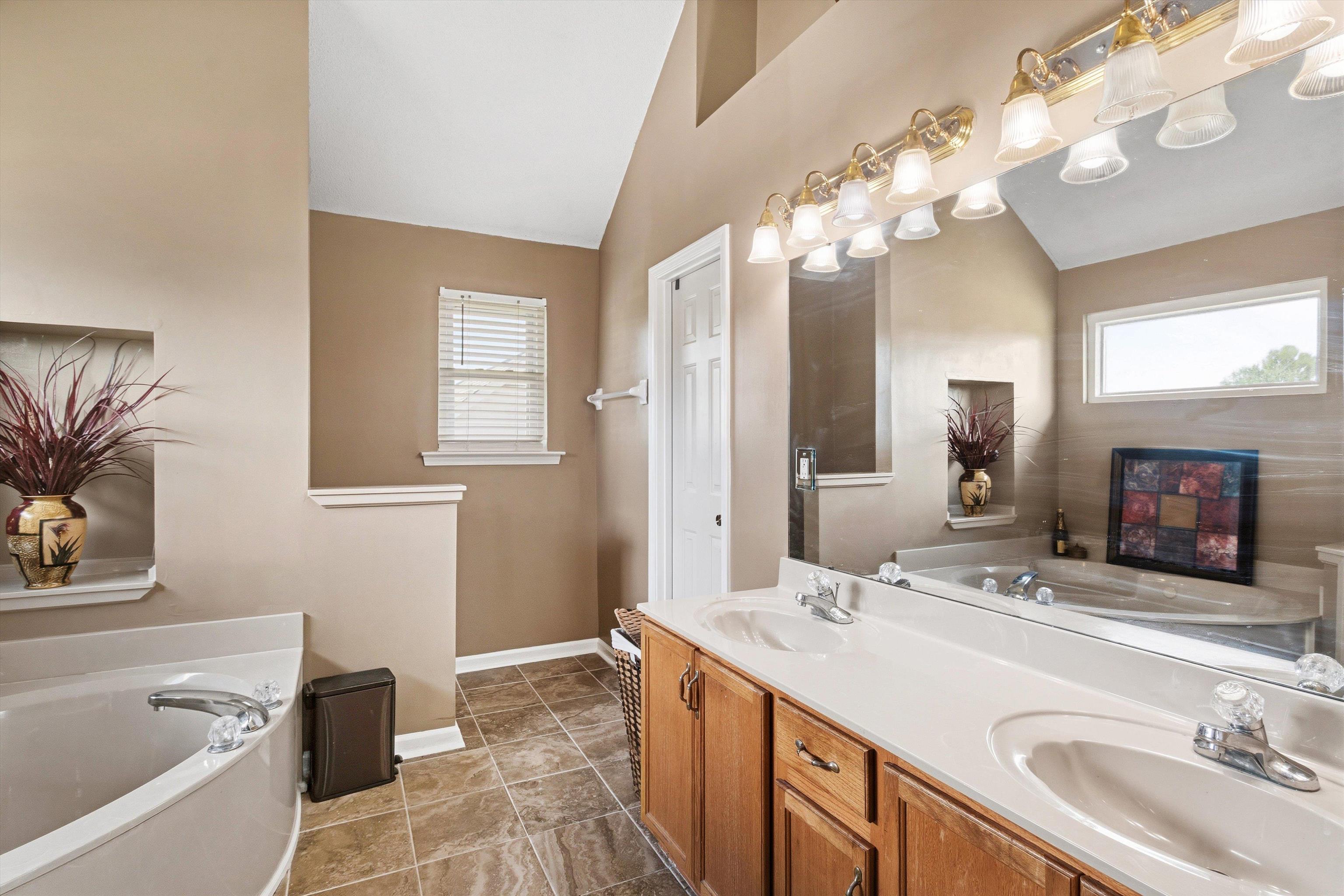 7779 Windy Willow Road Memphis, TN 38125 - Photo 15 of 30 Double vanity with integrated sinks and a large mirror, featuring a built-in garden tub and tiled flooring