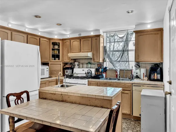 a kitchen with kitchen island a large counter top space appliances and a window