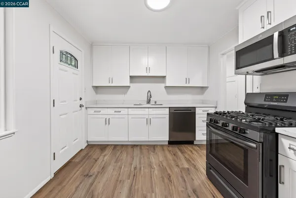 a kitchen with granite countertop a stove top oven a sink dishwasher and a refrigerator with wooden floor