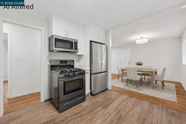 a kitchen with stainless steel appliances a stove a microwave a dining table and chairs