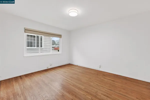 a view of an empty room with wooden floor and a window