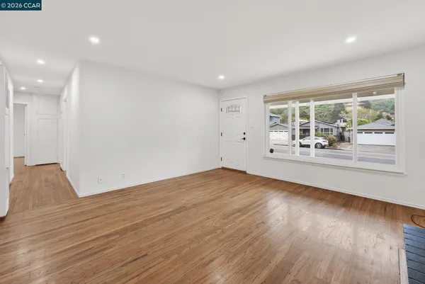 a view of an empty room with wooden floor and a window