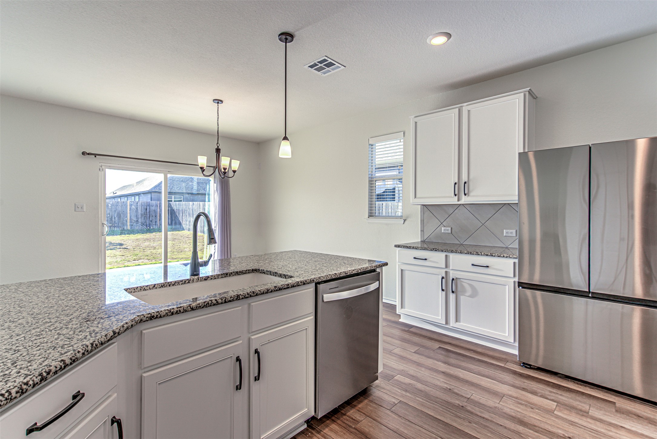 486 Gustaf Trail Kyle, TX 78640 - Photo 12 of 40 a kitchen with kitchen island granite countertop a sink a counter space appliances and cabinets