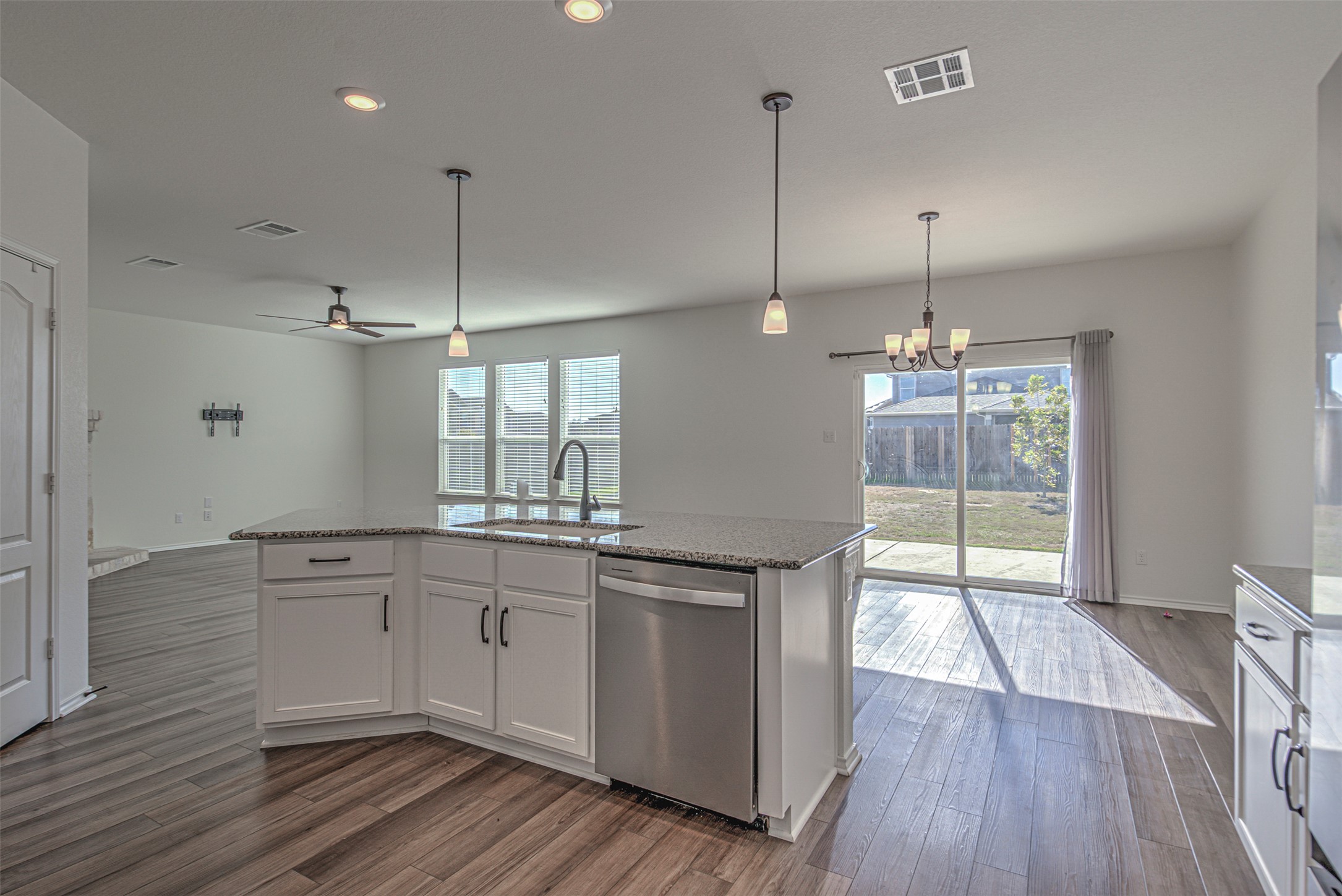 486 Gustaf Trail Kyle, TX 78640 - Photo 13 of 40 a large kitchen with granite countertop a stove a sink and white cabinets with wooden floor
