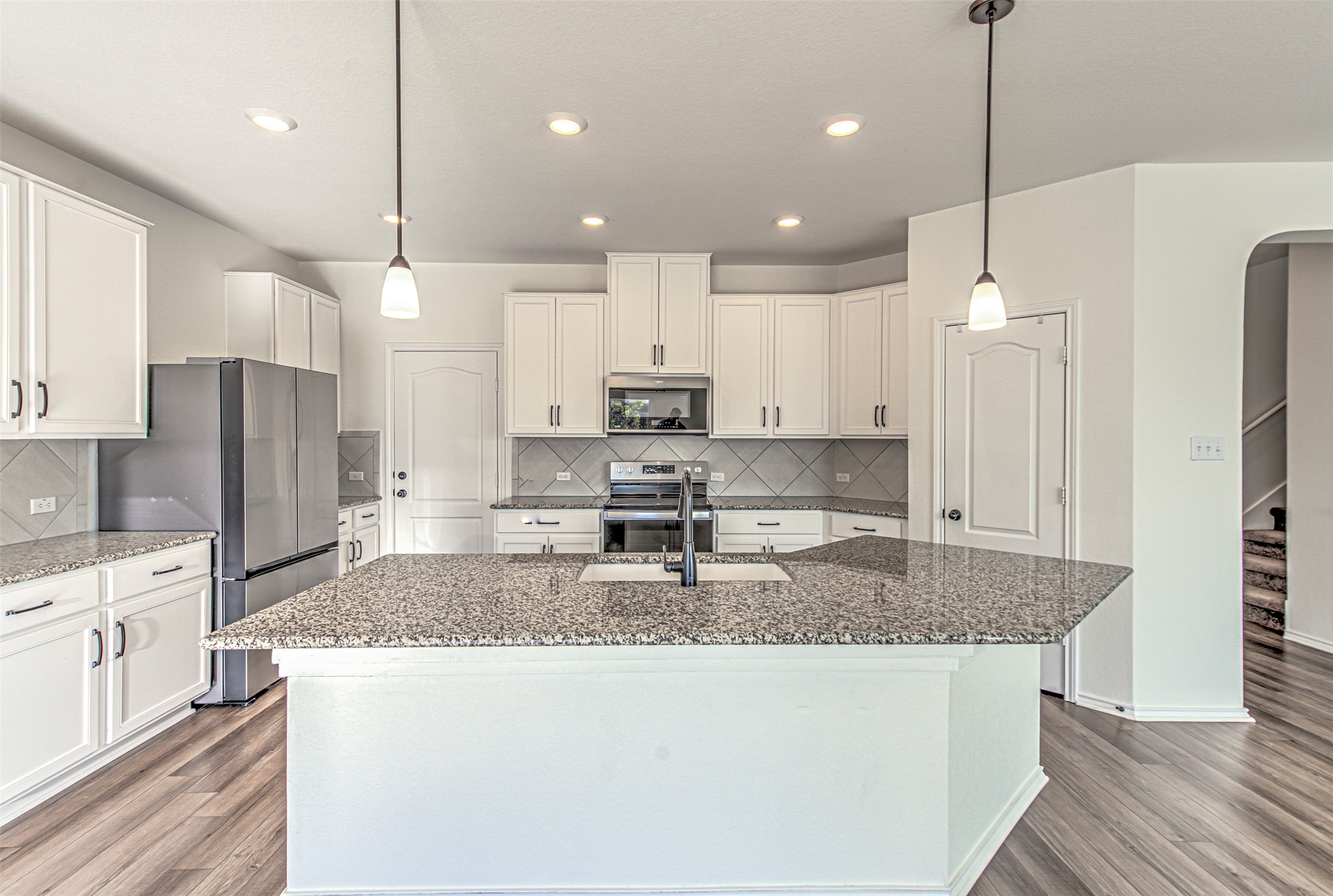 486 Gustaf Trail Kyle, TX 78640 - Photo 10 of 40 a kitchen with kitchen island granite countertop a sink a center island and stainless steel appliances