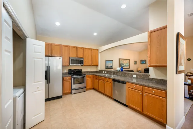 a kitchen with stainless steel appliances granite countertop a refrigerator a sink dishwasher a stove and a refrigerator
