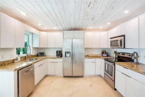 a kitchen with granite countertop stainless steel appliances and white cabinets