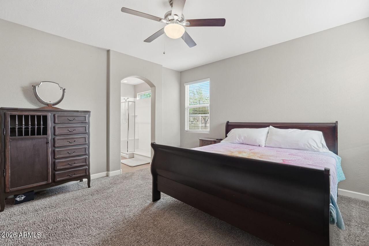 23602 West Ripple Road Buckeye, AZ 85326 - Photo 22 of 38 a spacious bedroom with a bed and a chandelier