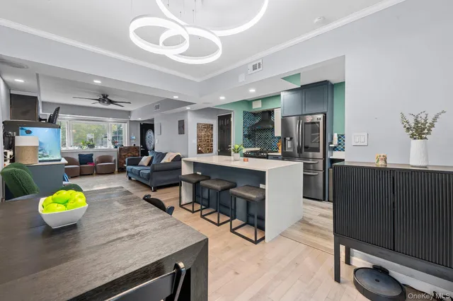 a living room with couches chairs and kitchen view with wooden floor