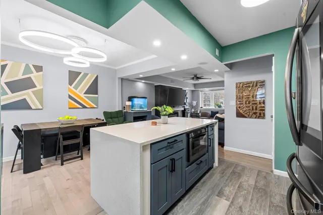 a kitchen with stainless steel appliances a stove a refrigerator a sink a dining table and chairs with wooden floor