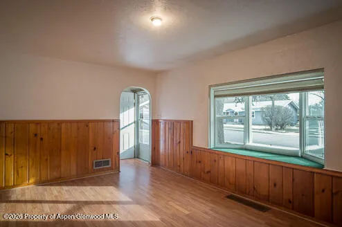 an empty room with wooden floor and windows