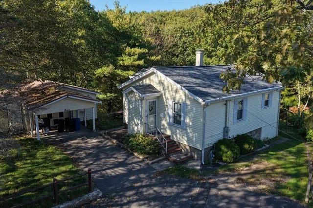 a view of house with yard outdoor seating and green bushes