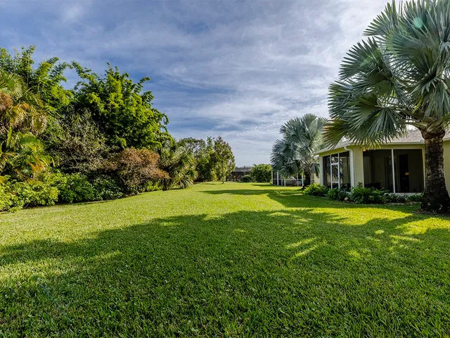 a view of a house with a big yard and palm trees