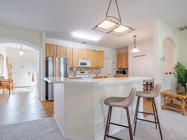 a kitchen with stainless steel appliances a refrigerator a stove a sink dishwasher and white cabinets with wooden floor