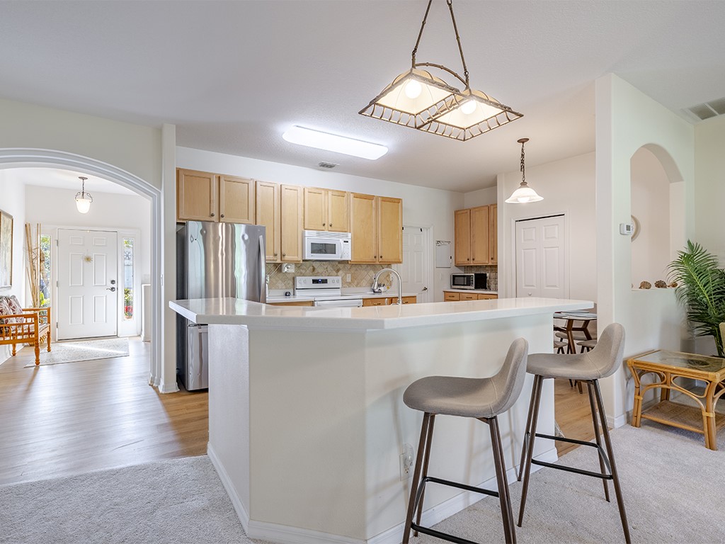 3648 2nd Street Southwest Vero Beach, FL 32968 - Photo 6 of 36 a kitchen with stainless steel appliances a refrigerator a stove a sink dishwasher and white cabinets with wooden floor