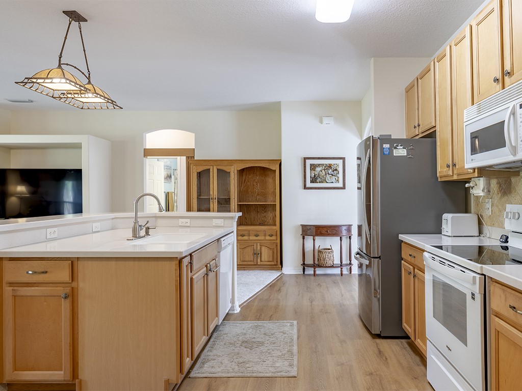 3648 2nd Street Southwest Vero Beach, FL 32968 - Photo 7 of 36 a kitchen with stainless steel appliances granite countertop a refrigerator a stove a sink dishwasher and wooden cabinets with wooden floor