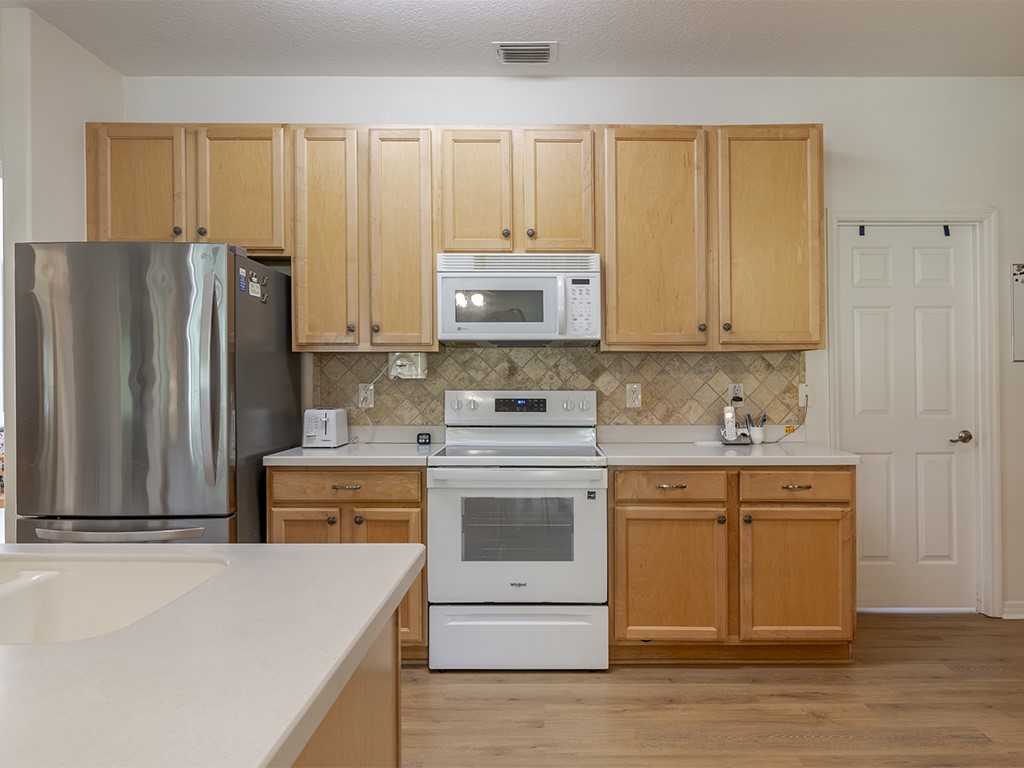 3648 2nd Street Southwest Vero Beach, FL 32968 - Photo 9 of 36 a kitchen with stainless steel appliances granite countertop a stove a sink and a refrigerator with wooden floors