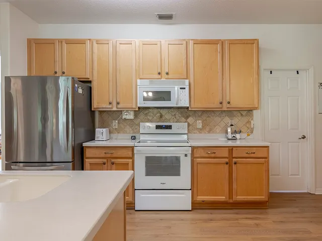 a kitchen with stainless steel appliances granite countertop a stove a sink and a refrigerator with wooden floors