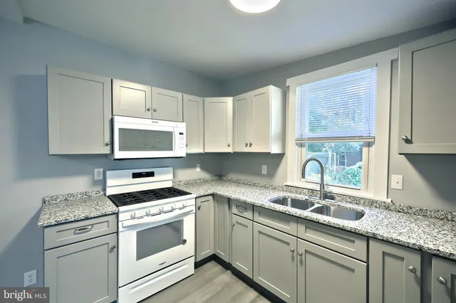 a kitchen with granite countertop a sink a stove a microwave and cabinets