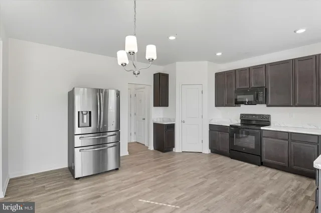 a view of a kitchen with stainless steel appliances a refrigerator and wooden floor