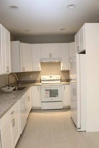 a kitchen with granite countertop white cabinets and white appliances