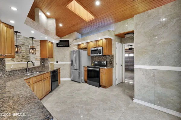 a large kitchen with stainless steel appliances kitchen island a large counter top a stove a refrigerator and a sink
