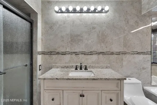 a bathroom with a granite countertop sink a toilet and a shower