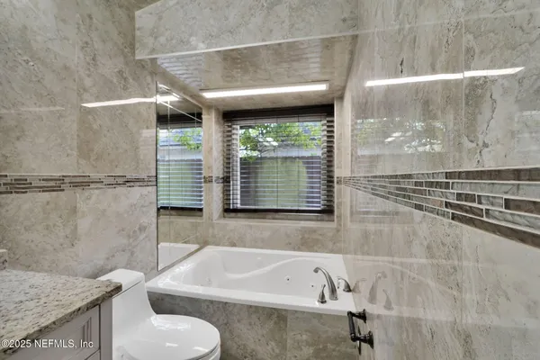 a bathroom with a tub a sink and a window