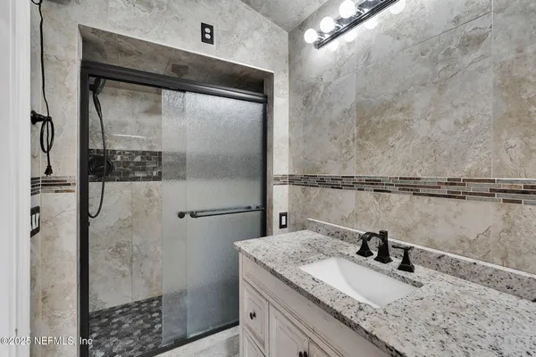 a bathroom with a granite countertop shower sink and mirror