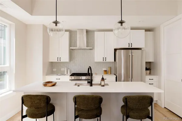 a kitchen with stainless steel appliances a sink a stove a refrigerator and white cabinets