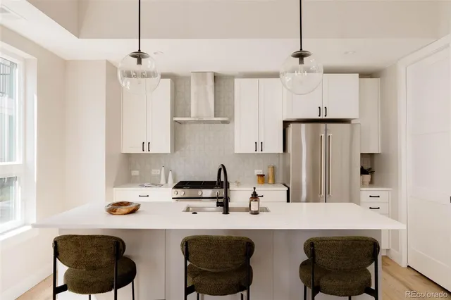 a kitchen with stainless steel appliances a sink a stove a refrigerator and white cabinets