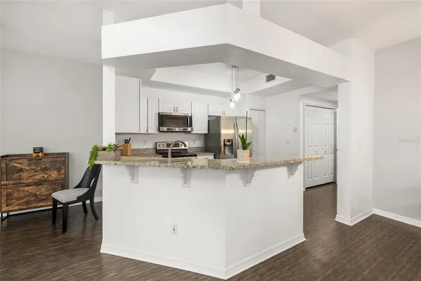 a view of kitchen with stainless steel appliances refrigerator stove dining table and chairs