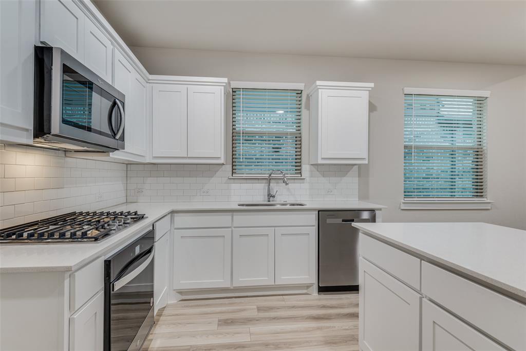 2544 Rambling Road Celina, TX 75009 - Photo 7 of 25 Kitchen with sink, white cabinets, tasteful backsplash, and appliances with stainless steel finishes