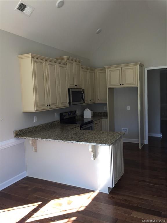 1854 State Rd S-46-168, Unit 4 York, SC 29745 - Photo 13 of 20 a kitchen with granite countertop a refrigerator a stove a sink and white cabinets with wooden floor