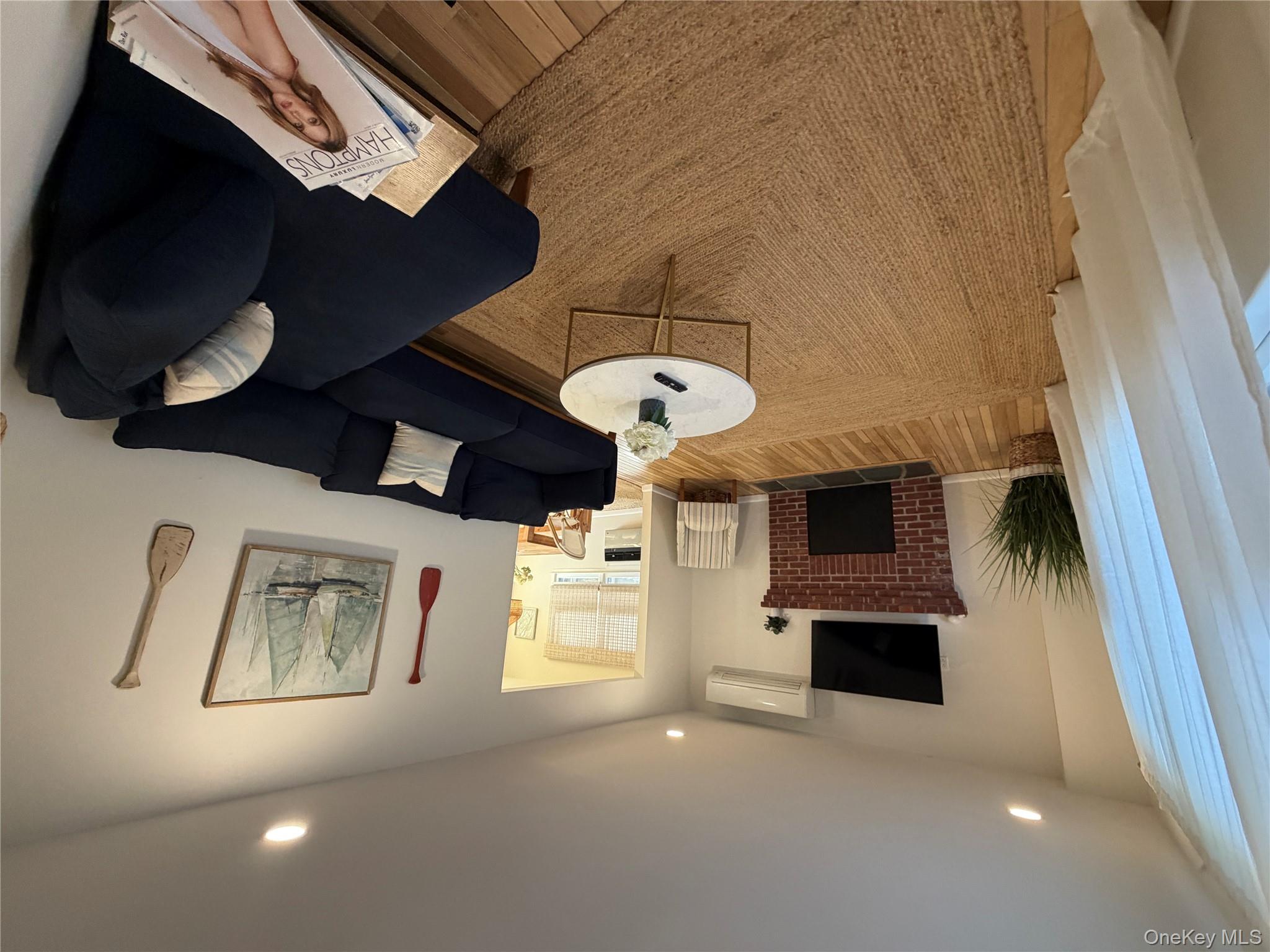 380 Eds Road Southold, NY 11971 - Photo 3 of 19 Living area featuring wood finished floors, a brick fireplace, recessed lighting, and an AC wall unit