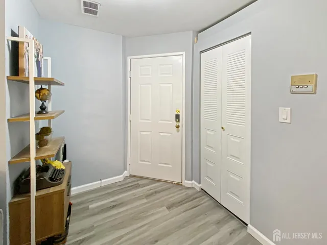 a view of an empty room with wooden floor and closet