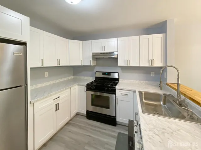 a kitchen with stainless steel appliances granite countertop a stove a sink and white cabinets