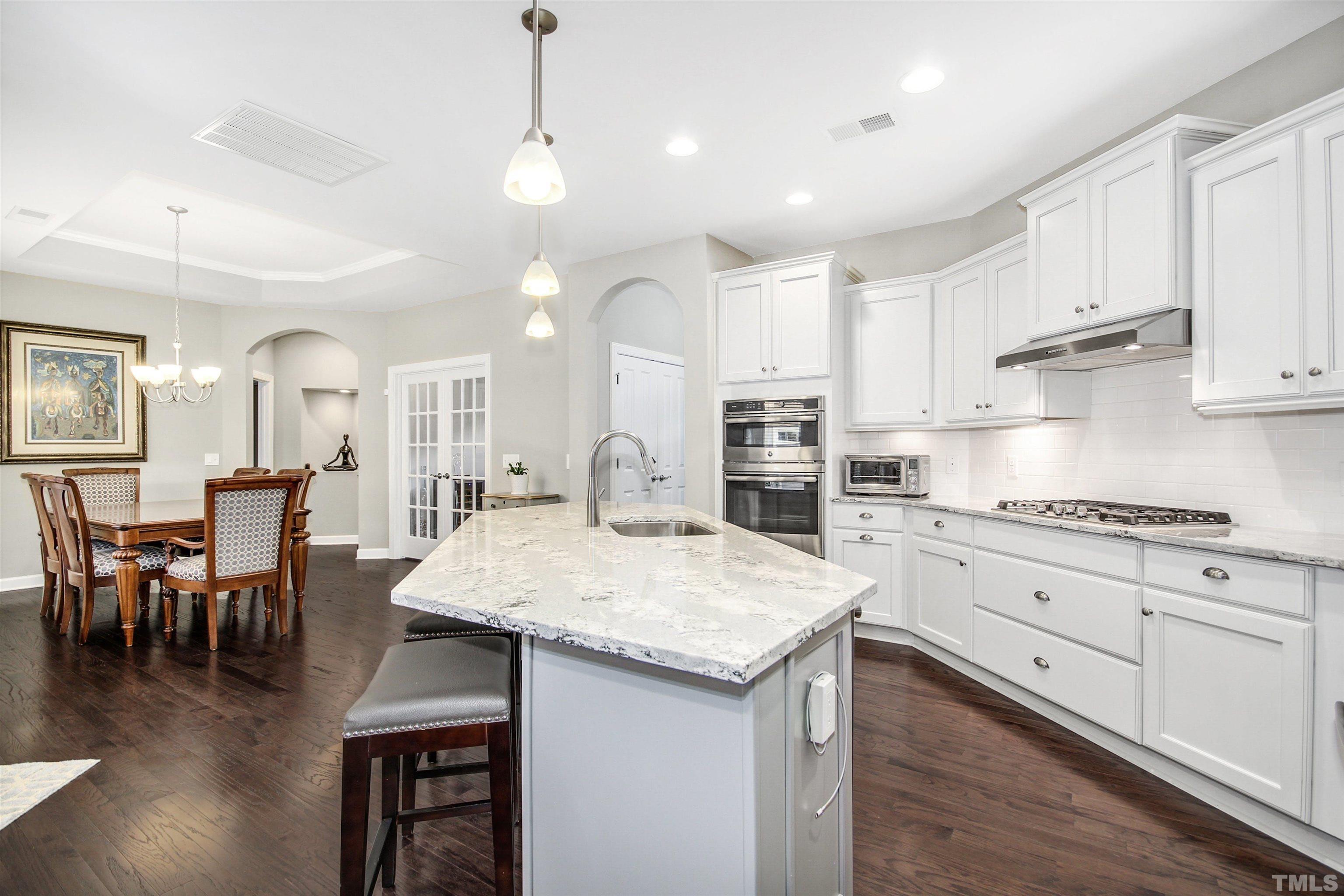 1313 Provision Place Wake Forest, NC 27587 - Photo 13 of 39 a kitchen with stainless steel appliances granite countertop a stove top oven a sink a dining table and chairs with wooden floor