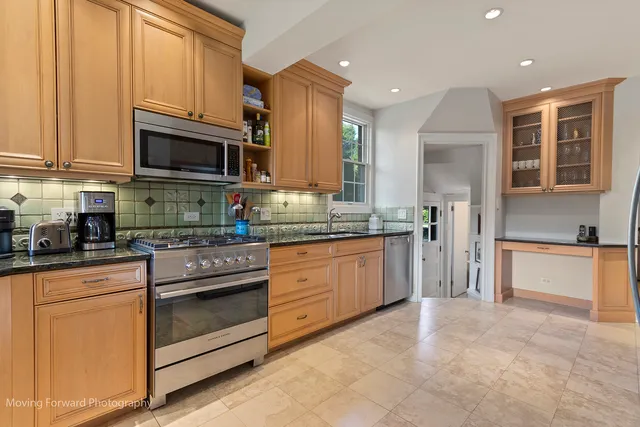 a kitchen with stainless steel appliances granite countertop a stove top oven a sink dishwasher and a refrigerator with wooden cabinets