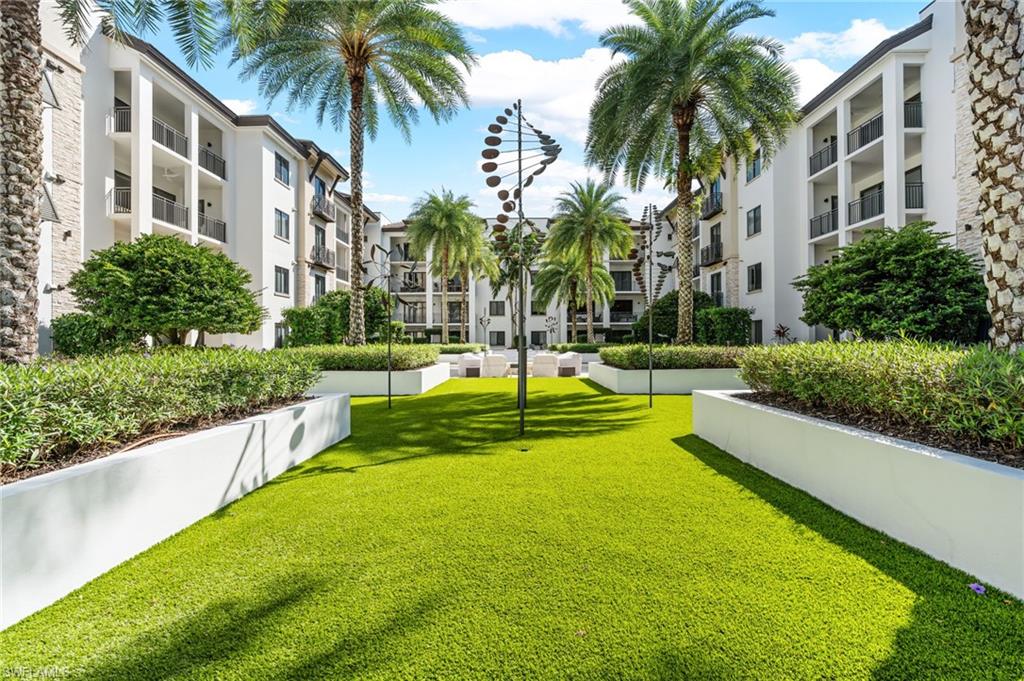 1030 3rd Avenue South, Unit 319 Naples, FL 34102 - Photo 28 of 42 a view of a swimming pool with a garden and palm trees