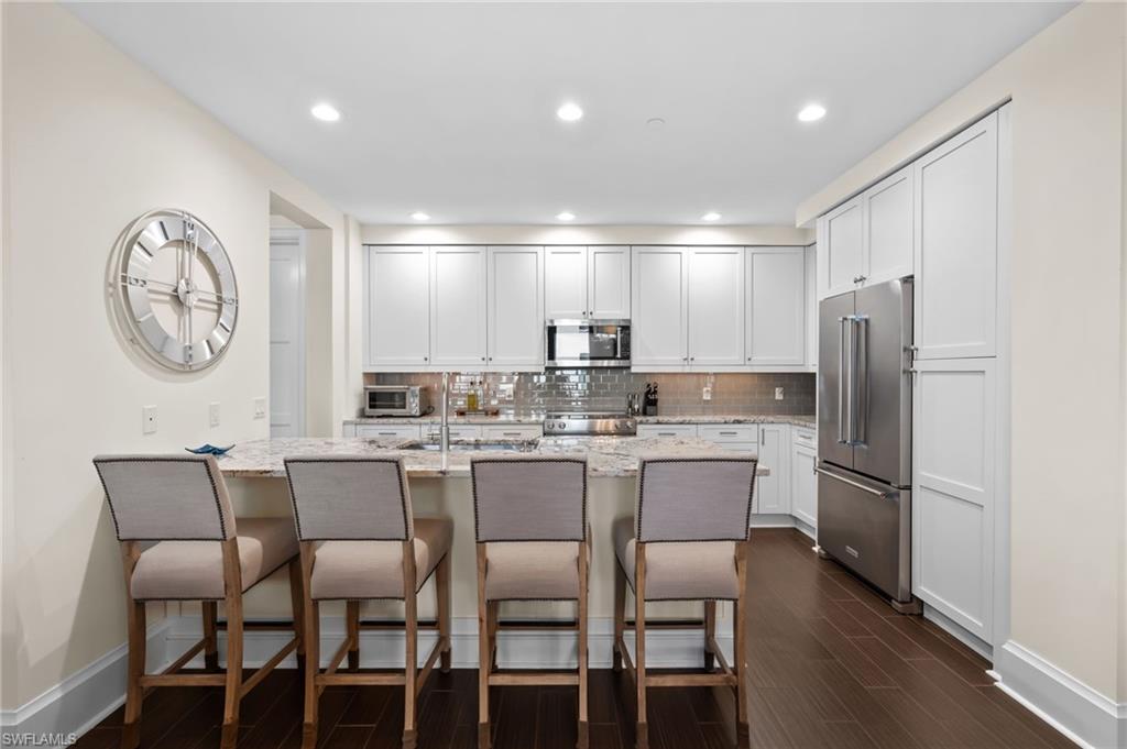 1030 3rd Avenue South, Unit 319 Naples, FL 34102 - Photo 5 of 42 a kitchen with a dining table chairs cabinets and stainless steel appliances