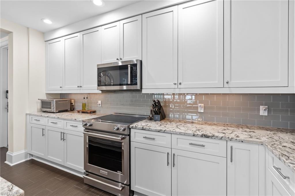 1030 3rd Avenue South, Unit 319 Naples, FL 34102 - Photo 8 of 42 a kitchen with granite countertop white cabinets and a stove top oven