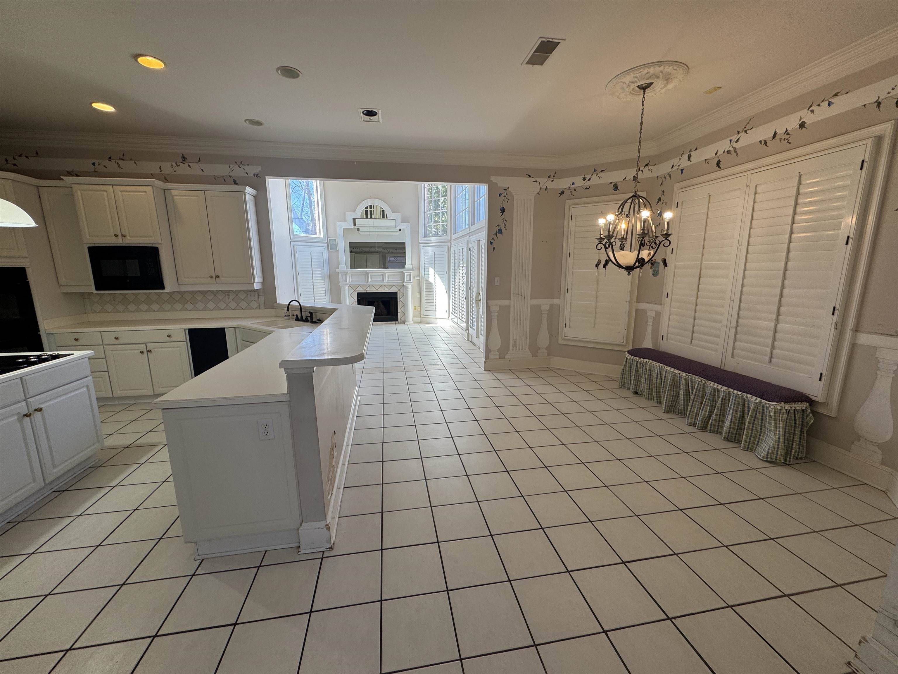 9500 Plantation Lake Road Collierville, TN 38017 - Photo 31 of 40 Kitchen featuring light tile patterned floors, a peninsula, a fireplace, crown molding, and black appliances