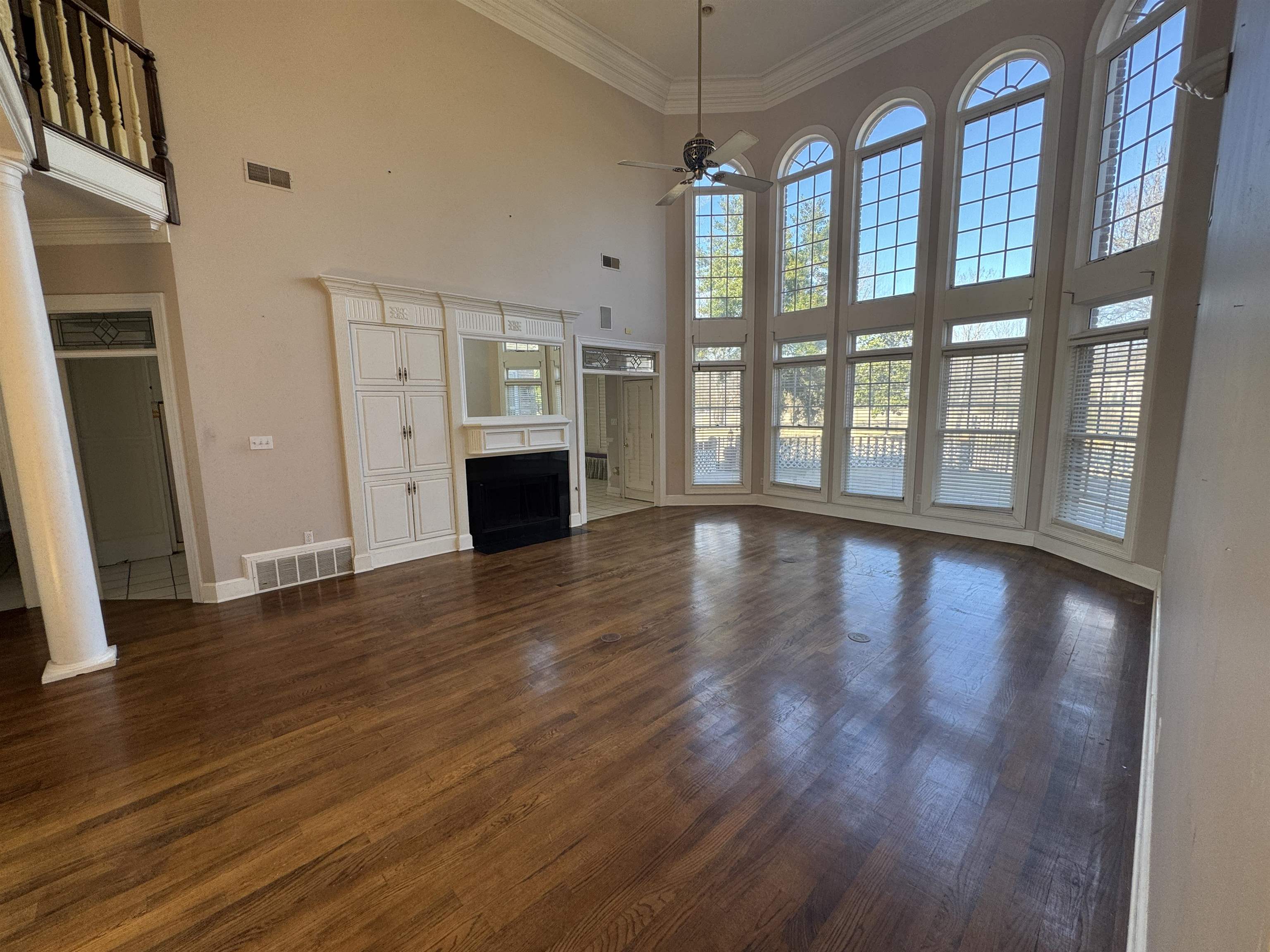 9500 Plantation Lake Road Collierville, TN 38017 - Photo 34 of 40 Unfurnished living room featuring visible vents, a ceiling fan, crown molding, a towering ceiling, and dark wood-type flooring
